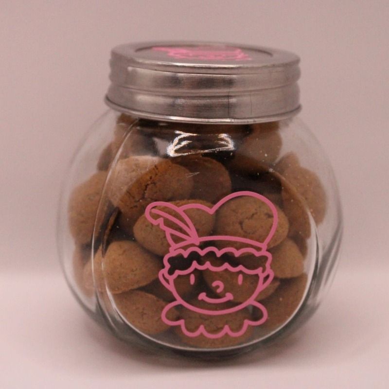 glazen potje met deksel, het potje is gevuld met pepernoten en heeft een roze sticker van een pietje op het potje en op de deksel- de kleur is naar wens aan te passen